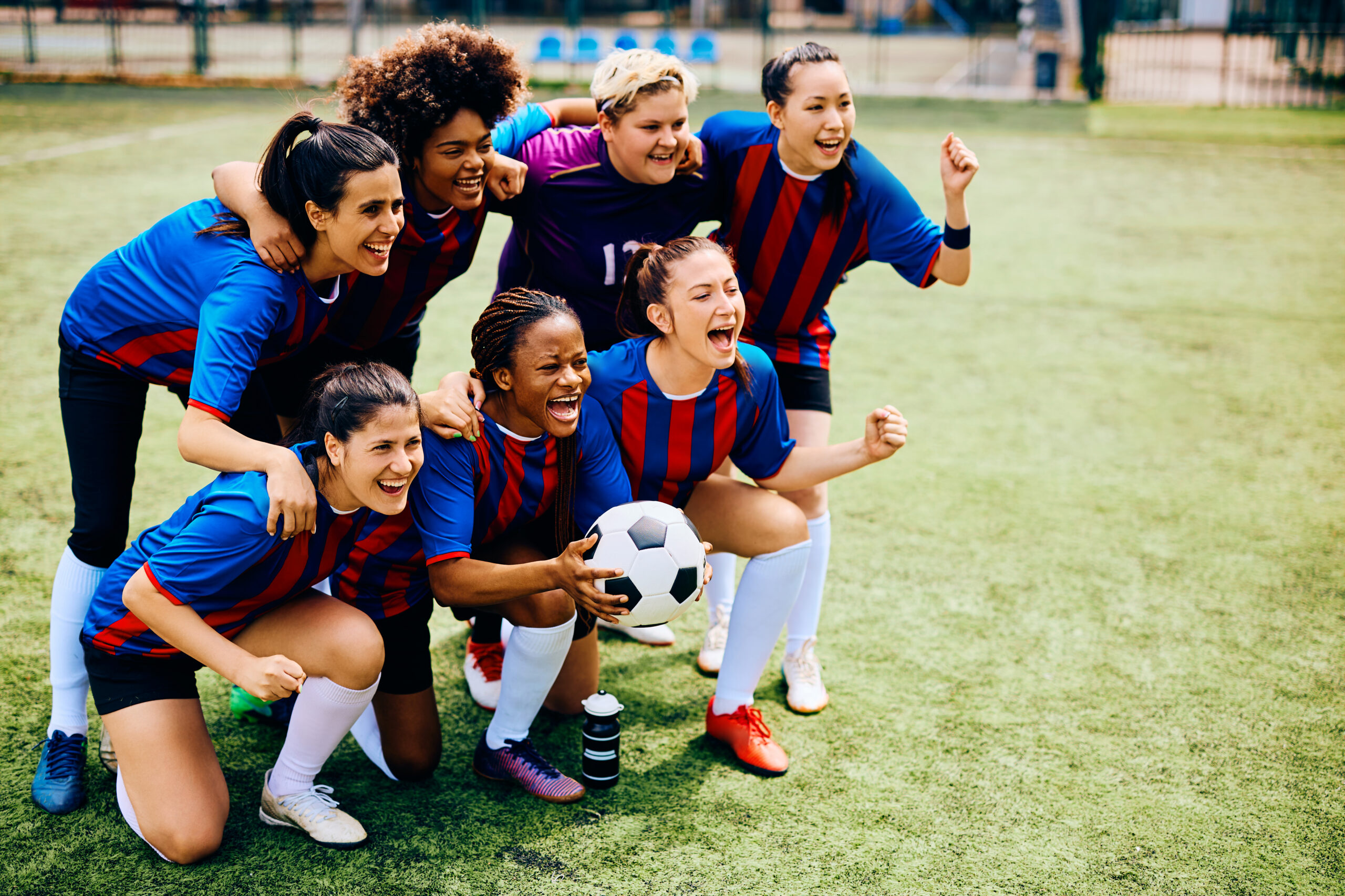 Cheerful women's soccer team screaming while celebrating winning the championship.