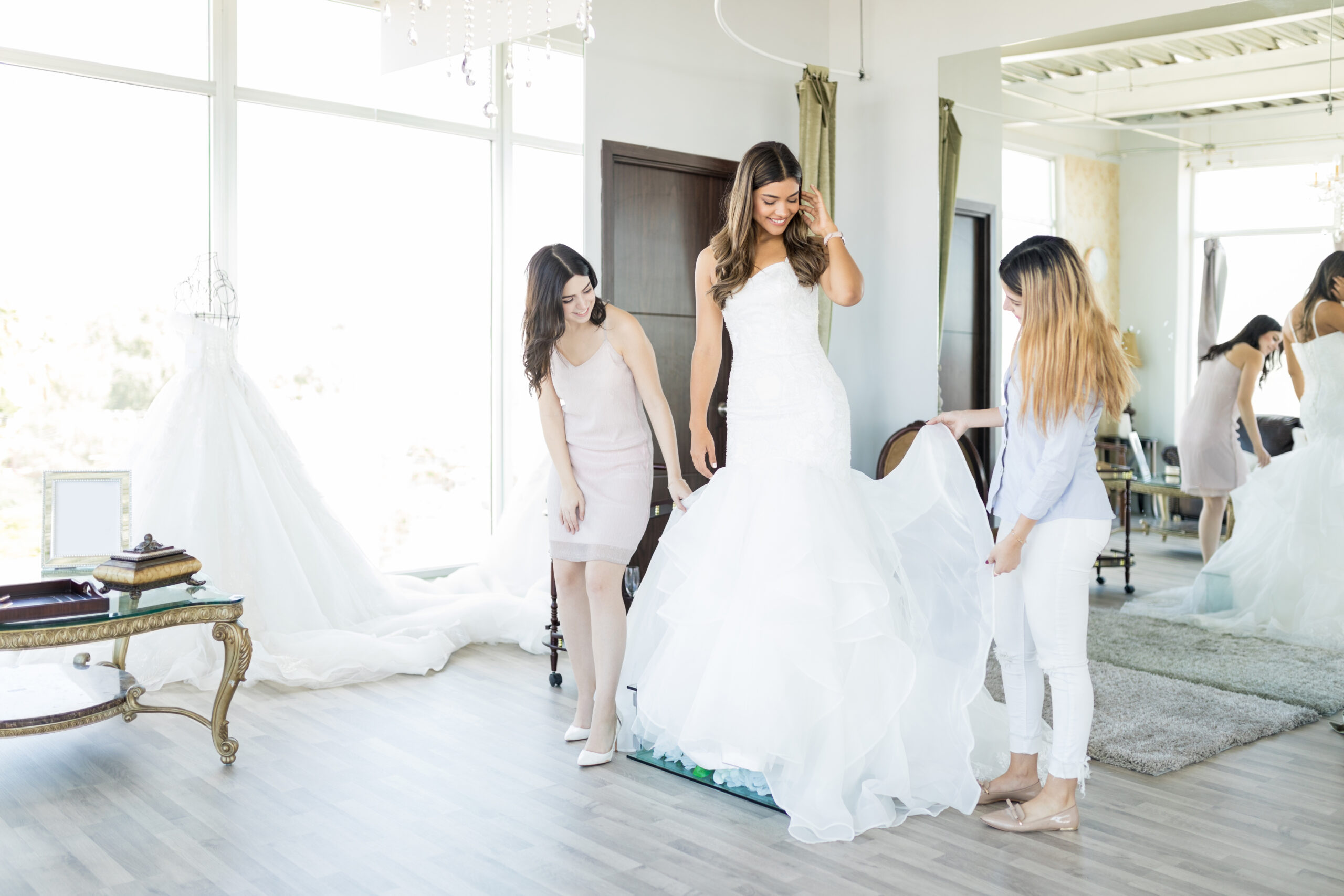Women Admiring White Wedding Gown In Store